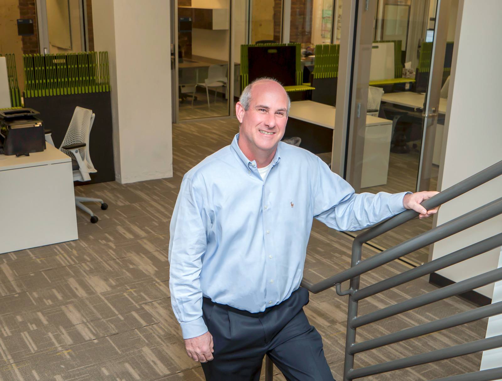 Chuck Denton, owner of Cellular Data Solutions, standing by a staircase in the office