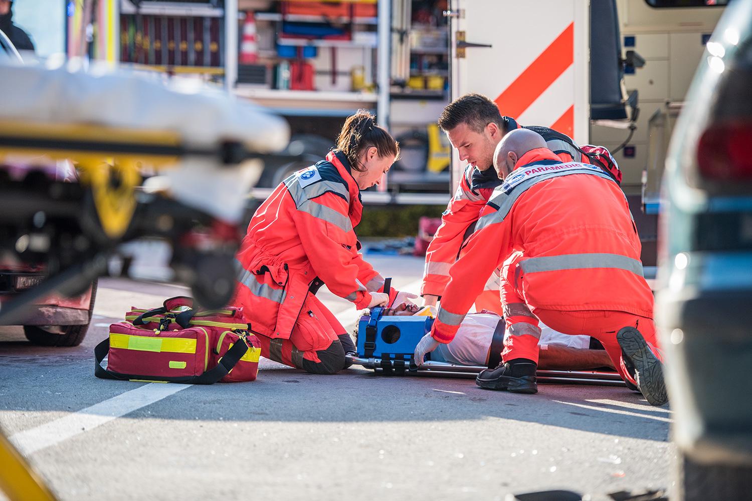 Paramedics treating a patient beside an ambulance